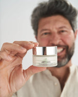 VOVEES Artemis crema antirughe in barattolo tenuta da uomo sorridente, skincare naturale e idratante viso.