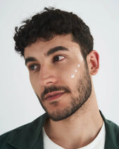 Uomo applica delicatamente la crema viso VOVEES CPR6 sulla guancia.