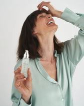 Donna sorridente tiene il siero viso VOVEES Athena.