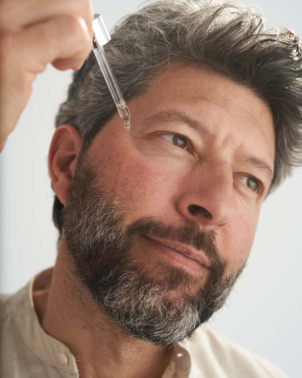 Uomo applica il siero viso VOVEES Lifting sulla guancia.