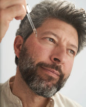 Uomo applica il siero viso VOVEES Lifting sulla guancia.
